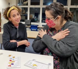 A girl and woman doing the Makaton sign for love. 