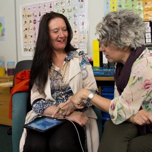 Two women having a Conversation. One has an iPad on her lap.